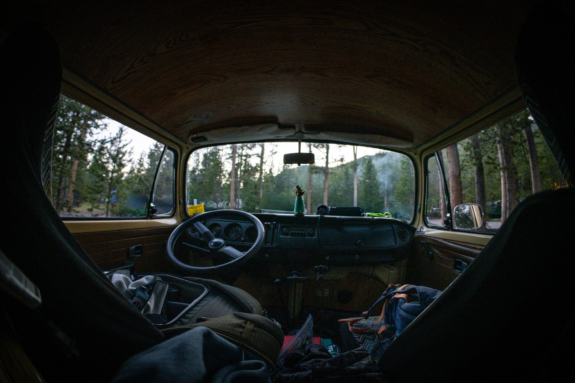 View through a vintage Volkswagen bus into a forest campsite